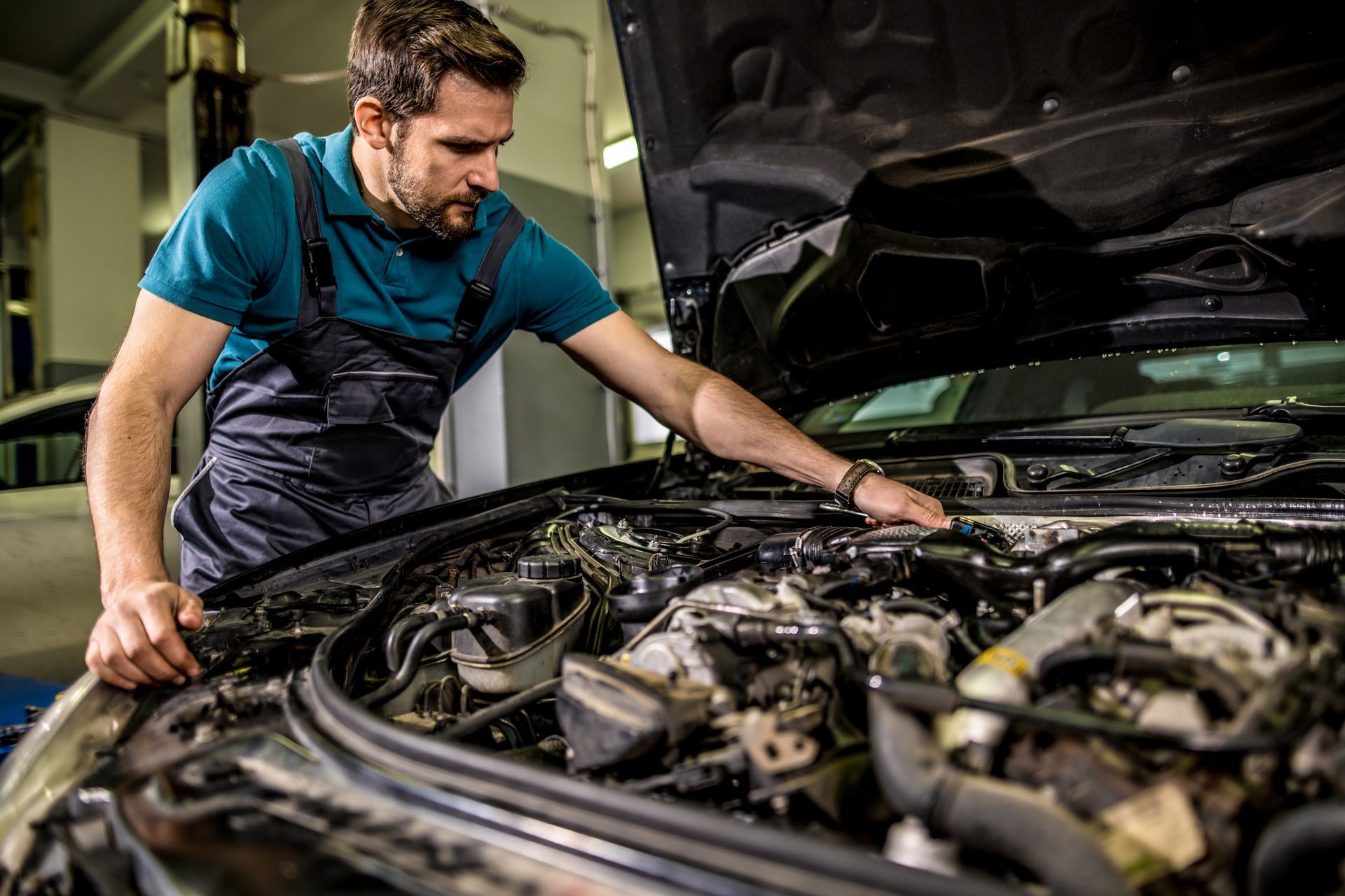 A man is working on the engine of a car in a garage.