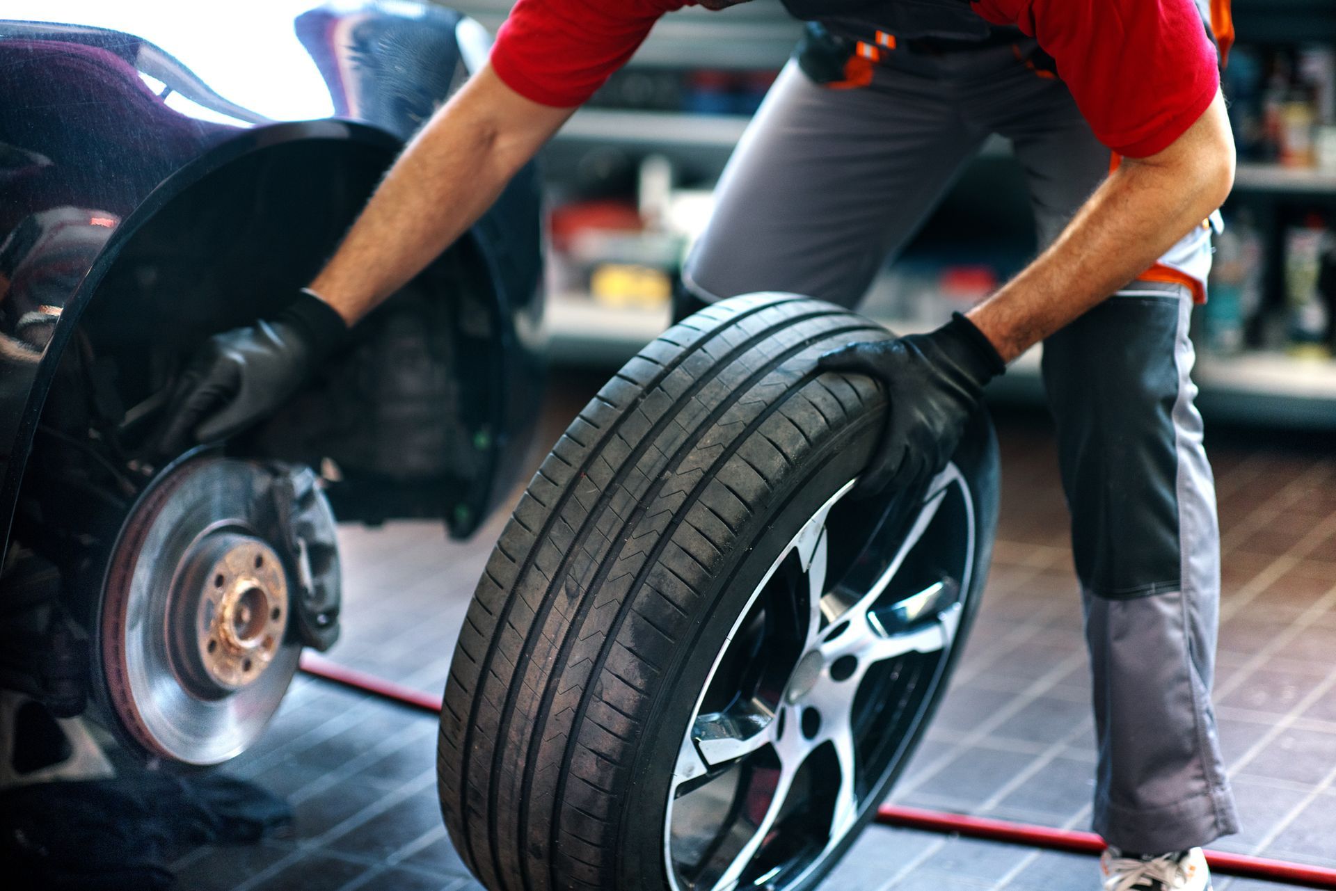 A man is changing a tire on a car in a garage.