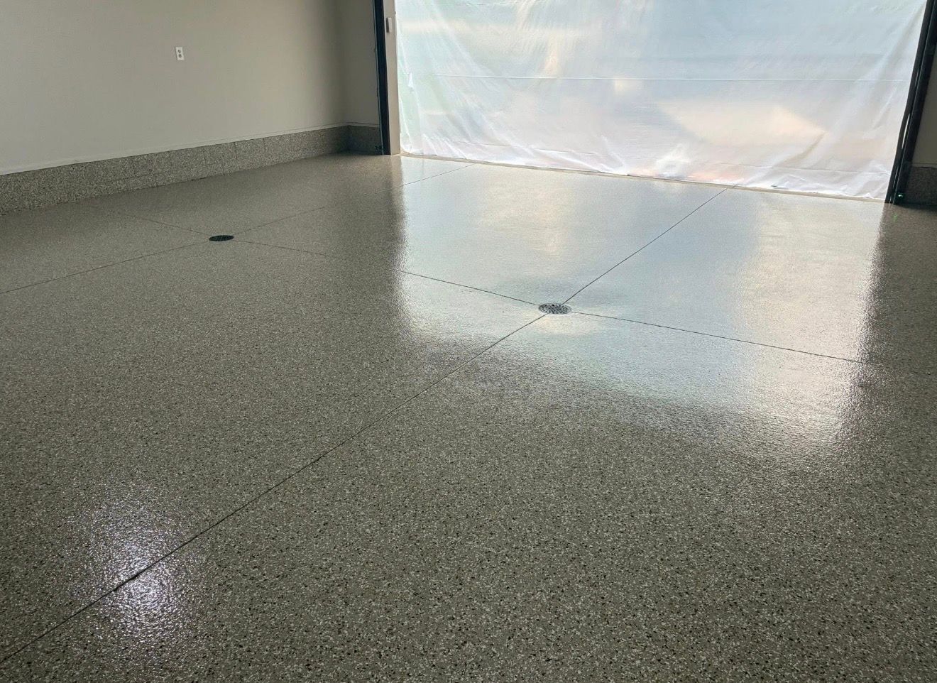 Shiny gray speckled floor in an empty room with a bright window opening