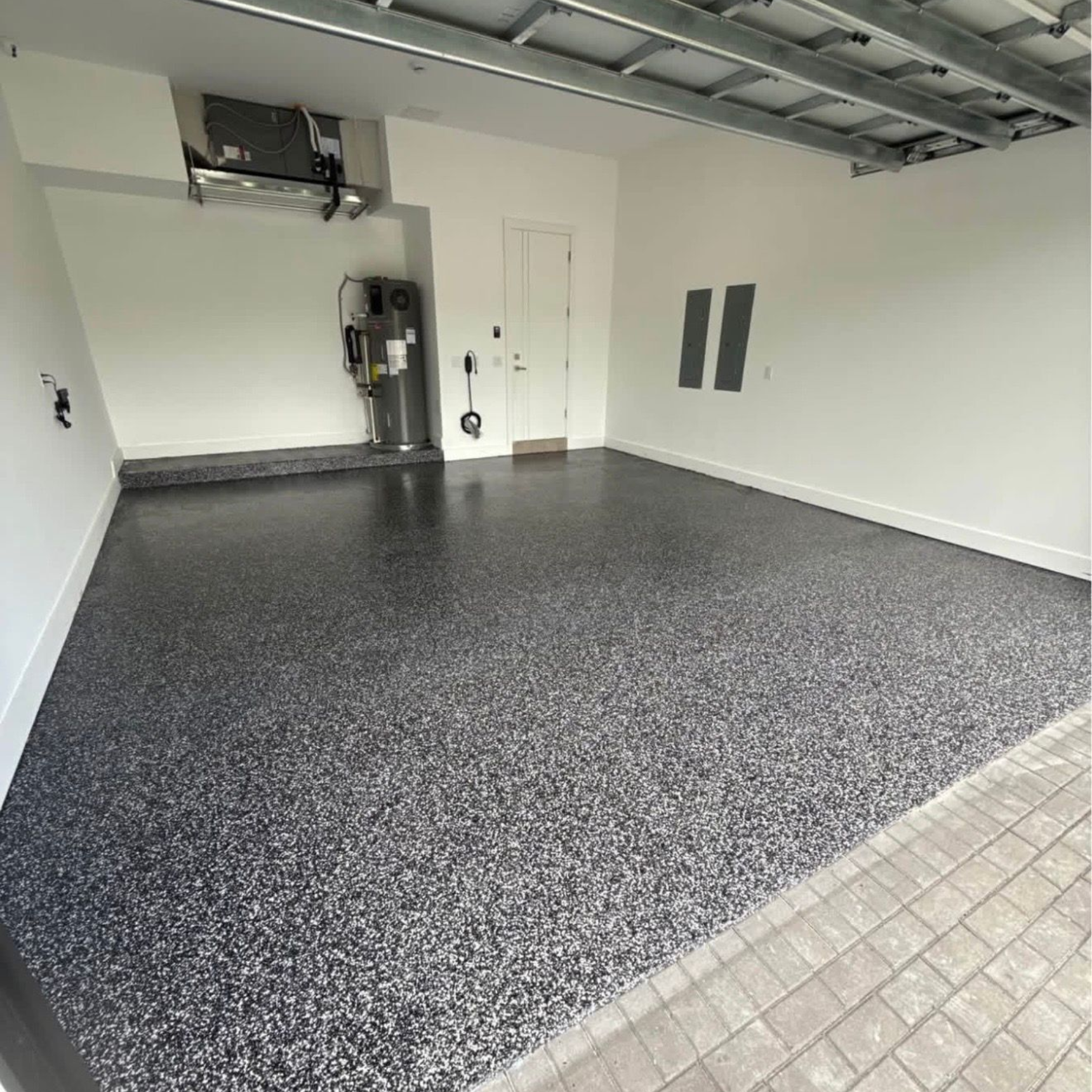 Empty garage with speckled black epoxy floor and white walls, viewed from the open doorway