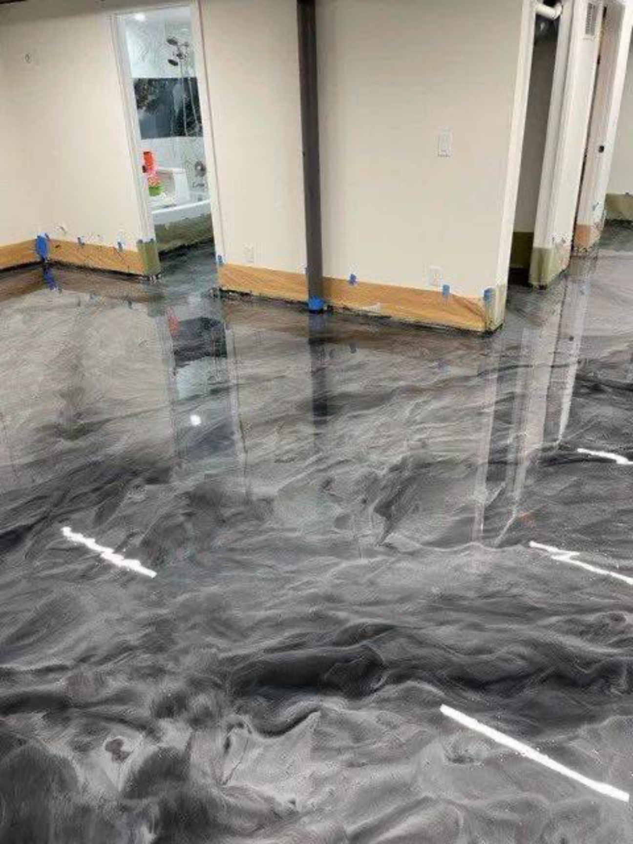 Shiny black-and-gray marbled floor in a hallway with beige walls and doorways