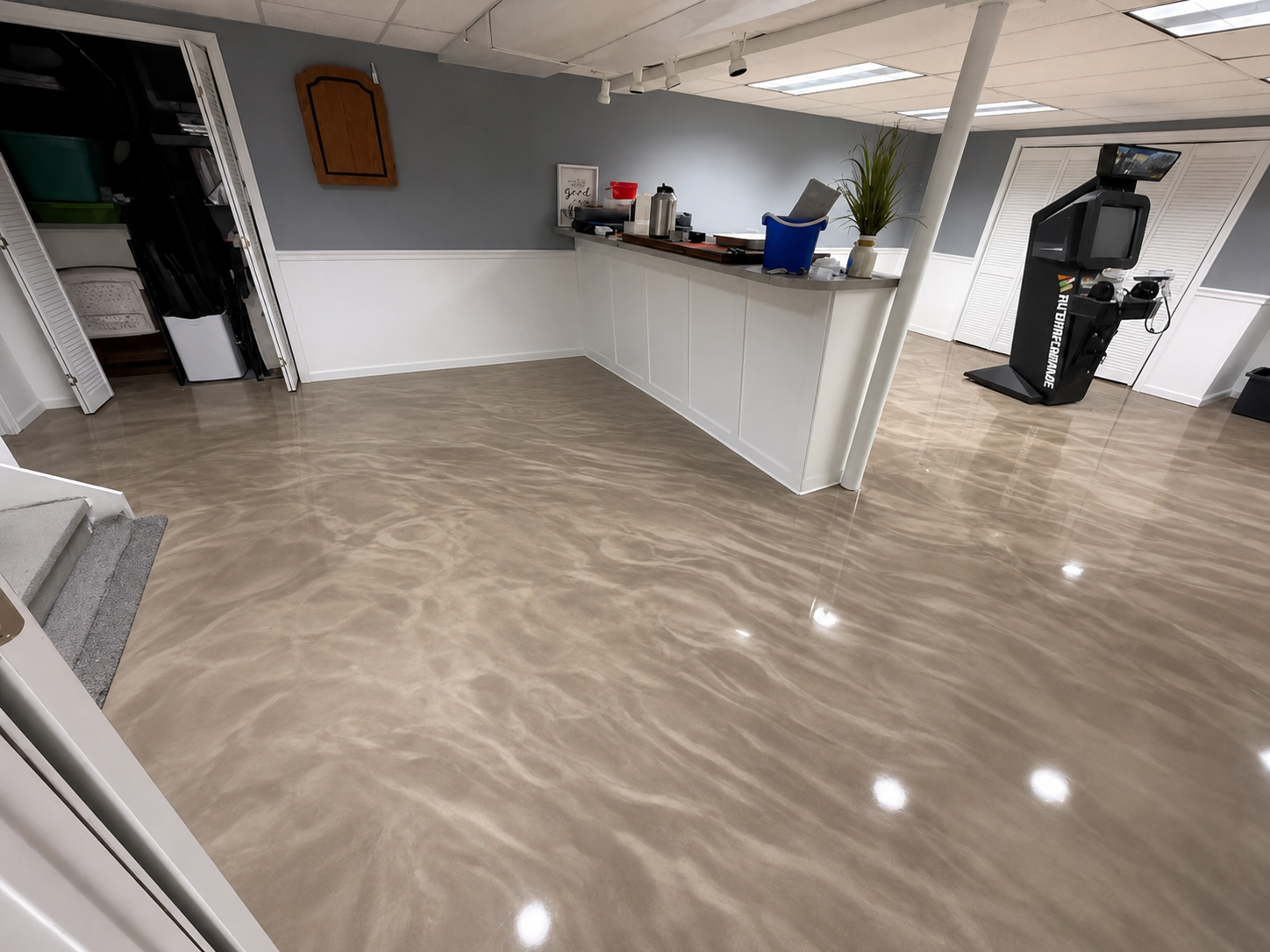 Empty kitchen or break room with beige floor, white counter, gray walls, and a coffee maker on the right.