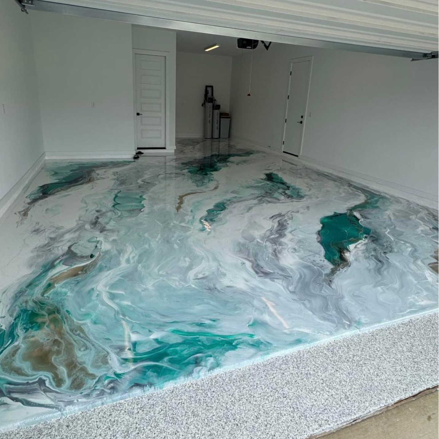 Garage floor with teal and white epoxy-style marbling under a partially open door