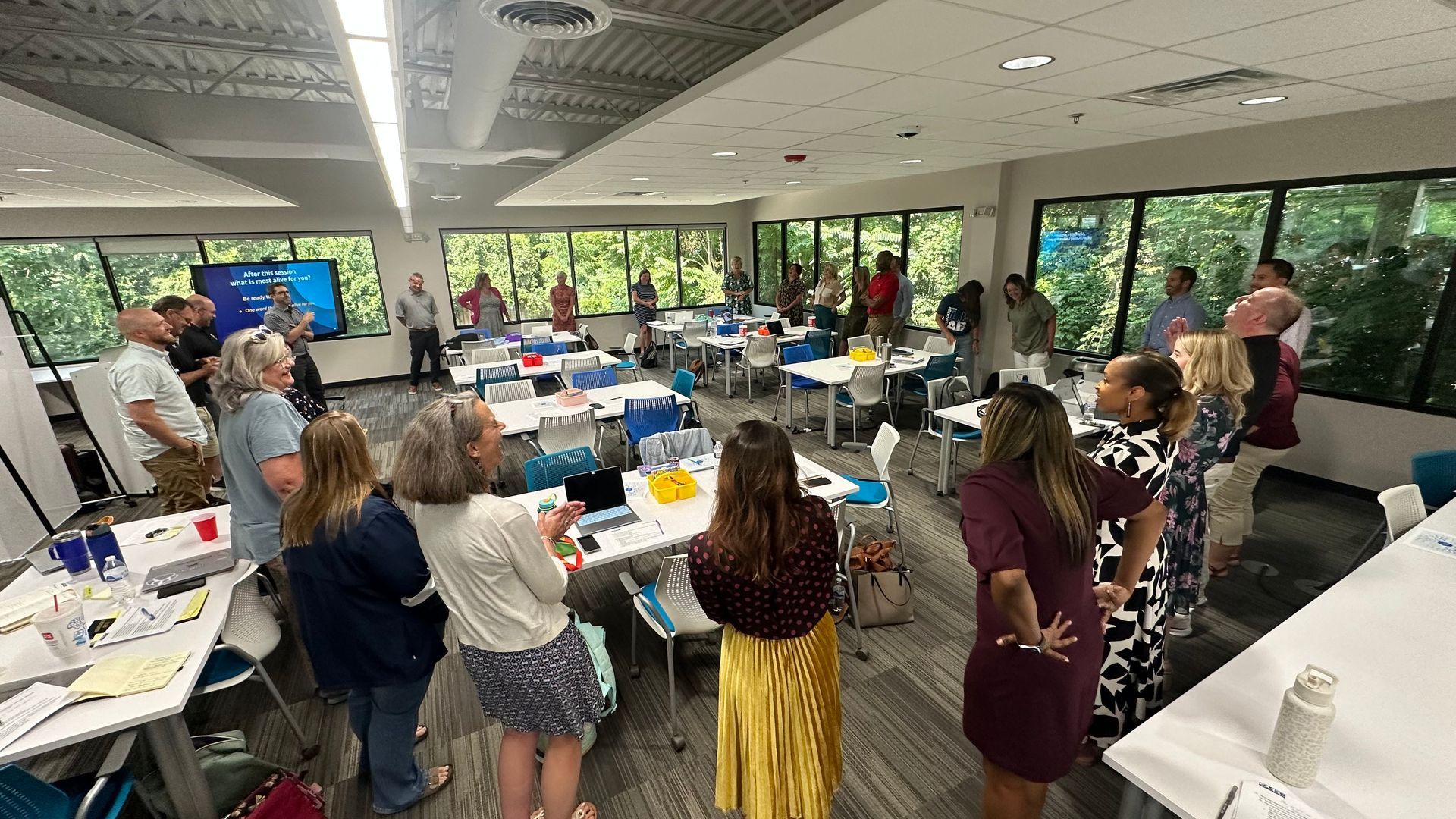 A group of people are standing in a room with tables and chairs.