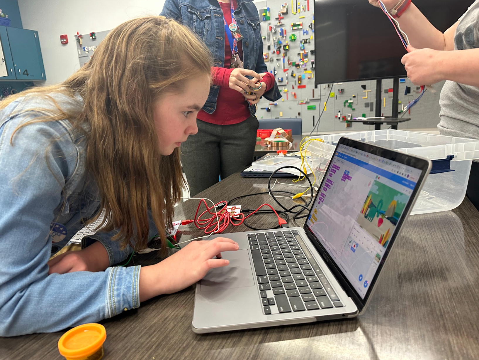 A girl is using a laptop computer on a table.