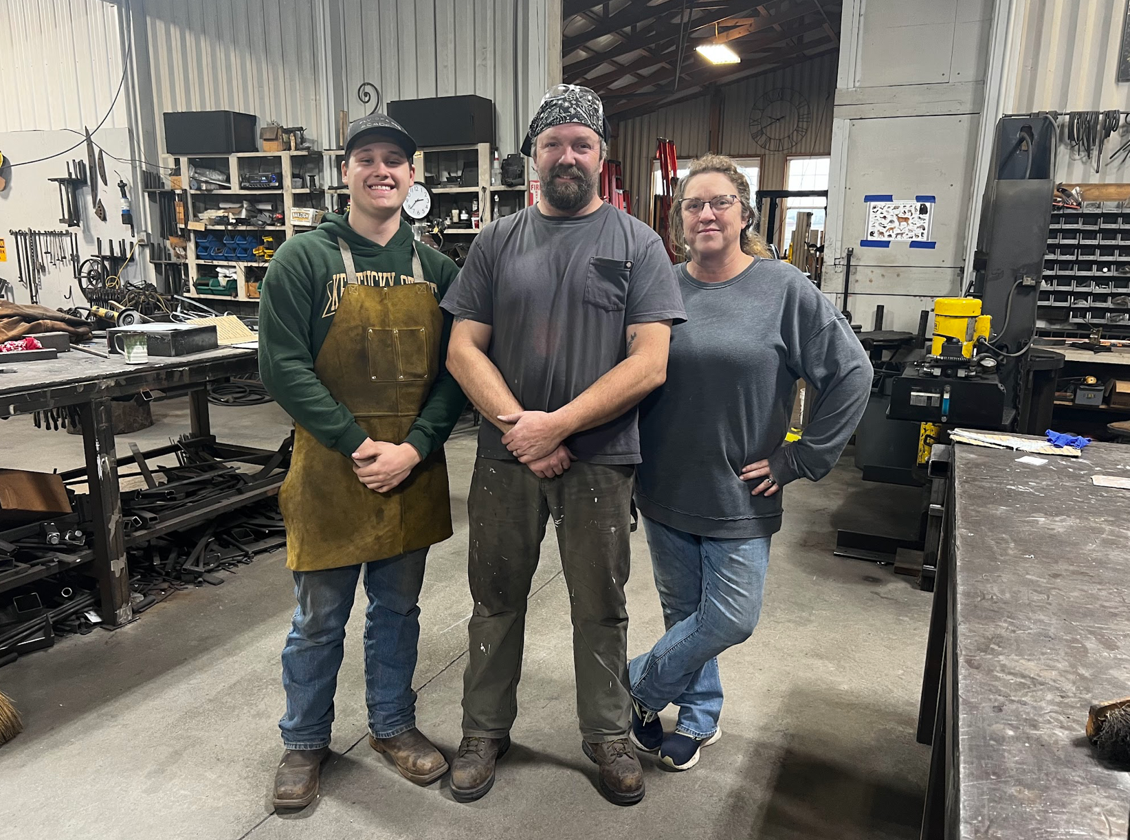 Three people are posing for a picture in a workshop.