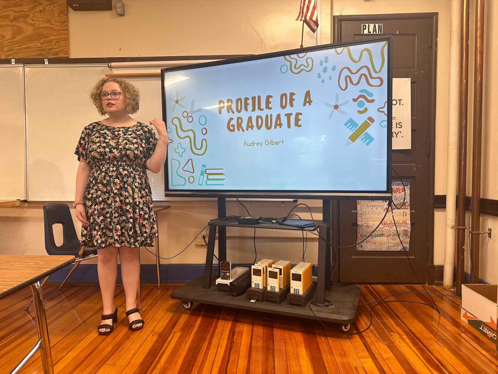 A woman is standing in front of a large screen that says profile of a graduate