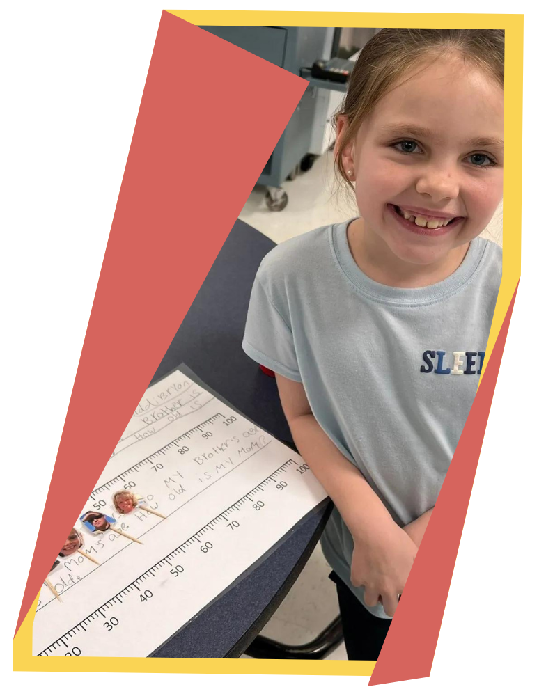 Young girl smiles in front of school work