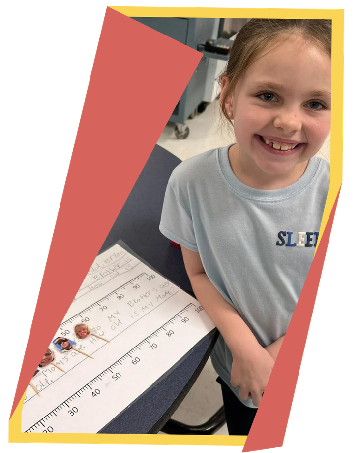 Young girl smiles in front of school work
