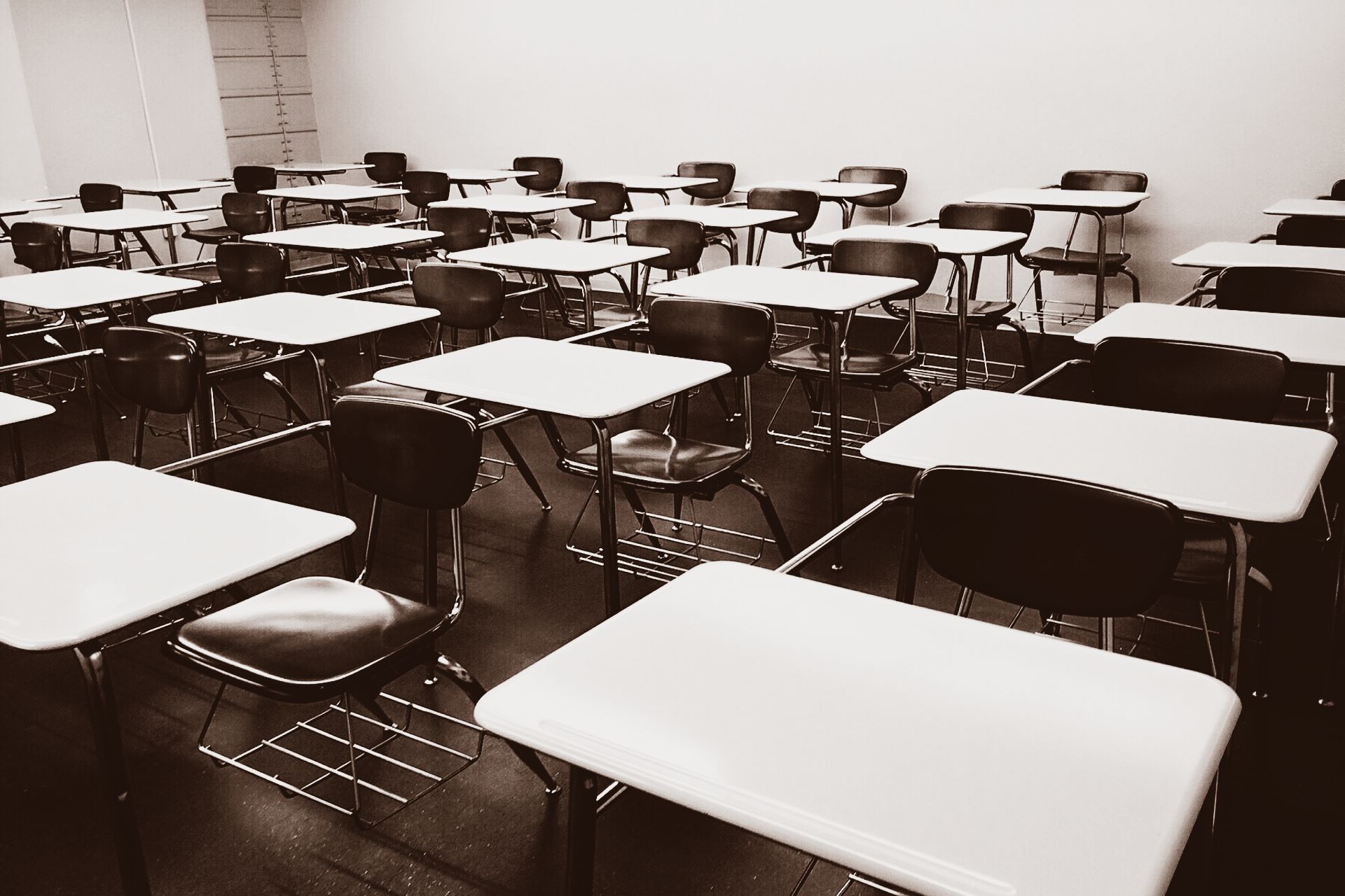 An empty classroom with white tables and black chairs