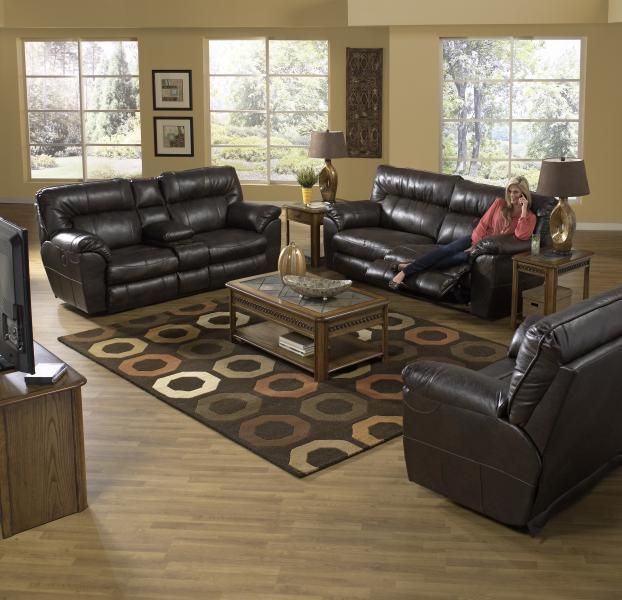 Living room with dark leather sectional, matching recliner, coffee table, and a person sitting on the sofa