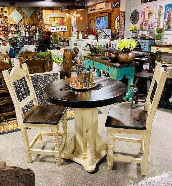 Rustic cafe display with round wooden tables, cream chairs, flowers, and wall art in a cozy shop interior