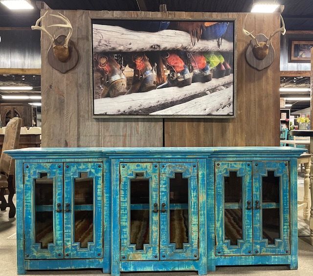 Turquoise distressed cabinet beneath a framed fish art display in a rustic store interior