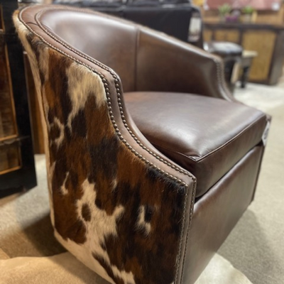 Brown leather accent chair with cowhide-patterned sides and nailhead trim in a showroom