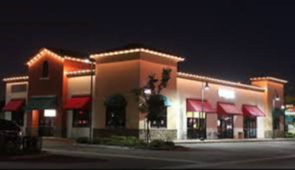 A building with red awnings is lit up at night with permanent lights