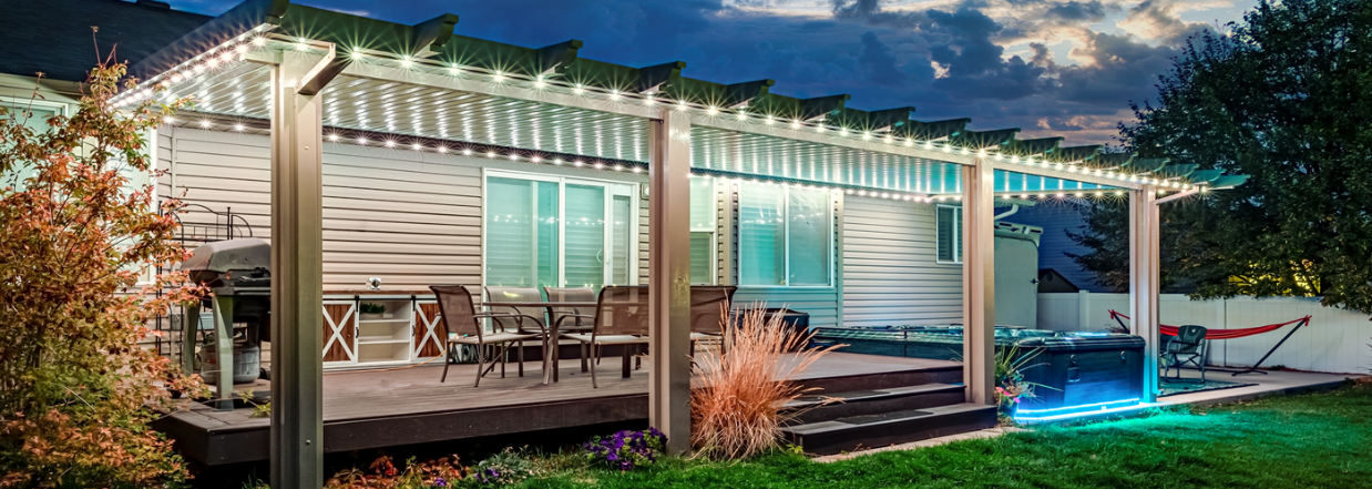 A house with a pergola and lights on it at night.