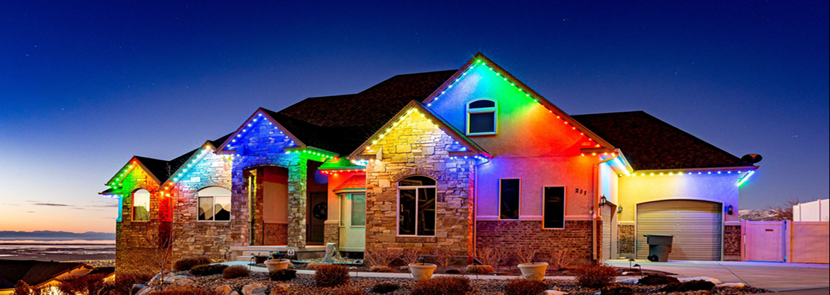 A large house is decorated with rainbow colored permanent Christmas lights.