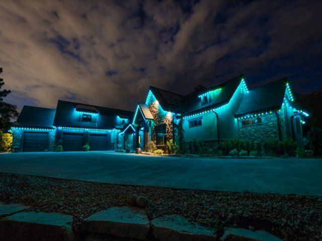 A large house is lit up with blue permanent lighting