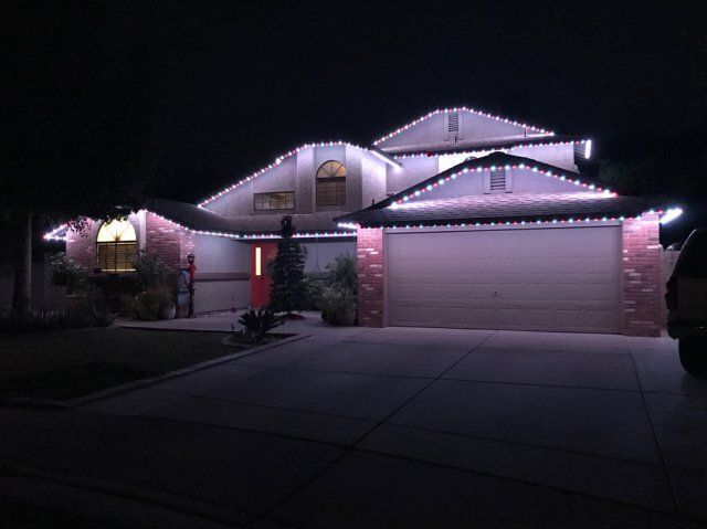 A house with permanent Christmas lights on it is lit up at night.