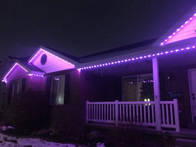 A house with purple permanent lights on the porch and roof