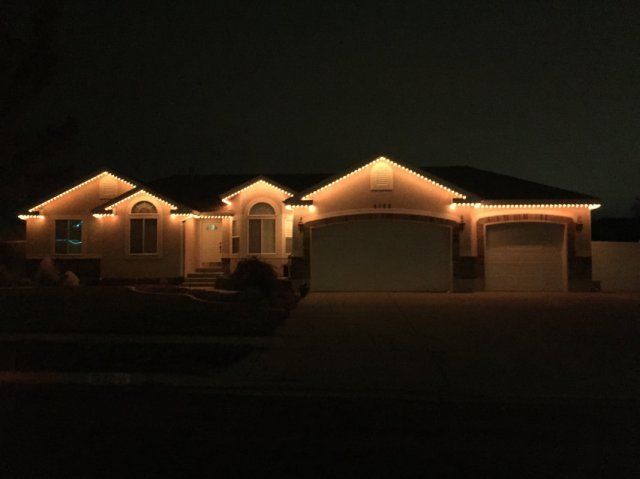 A house is lit up at night with permanent Christmas lights.