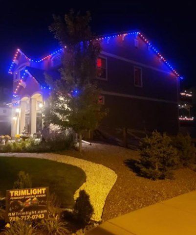 A house with permanent Christmas lights on it is lit up at night.