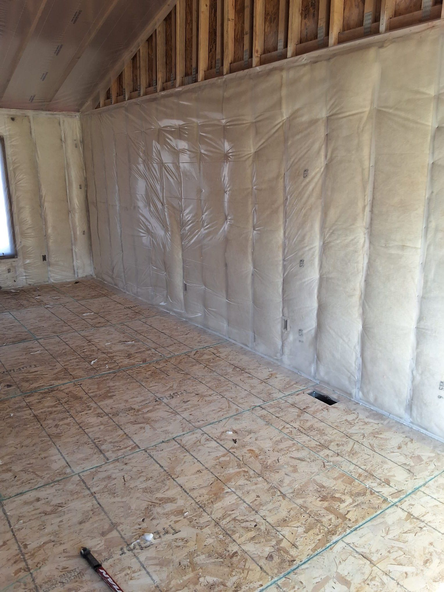 Furnace in a utility room, metal and gray, against a white wall and a gray floor.