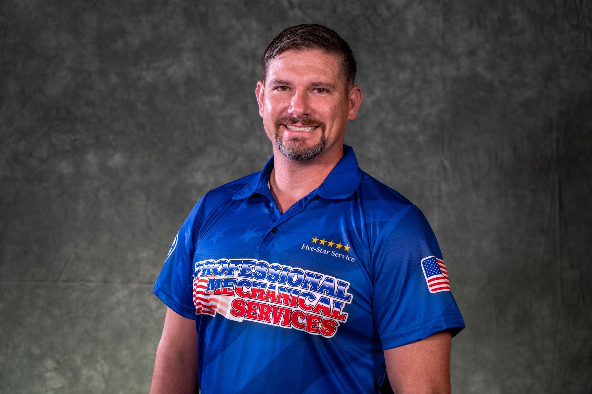 A man wearing a hat and a polo shirt is smiling for the camera.