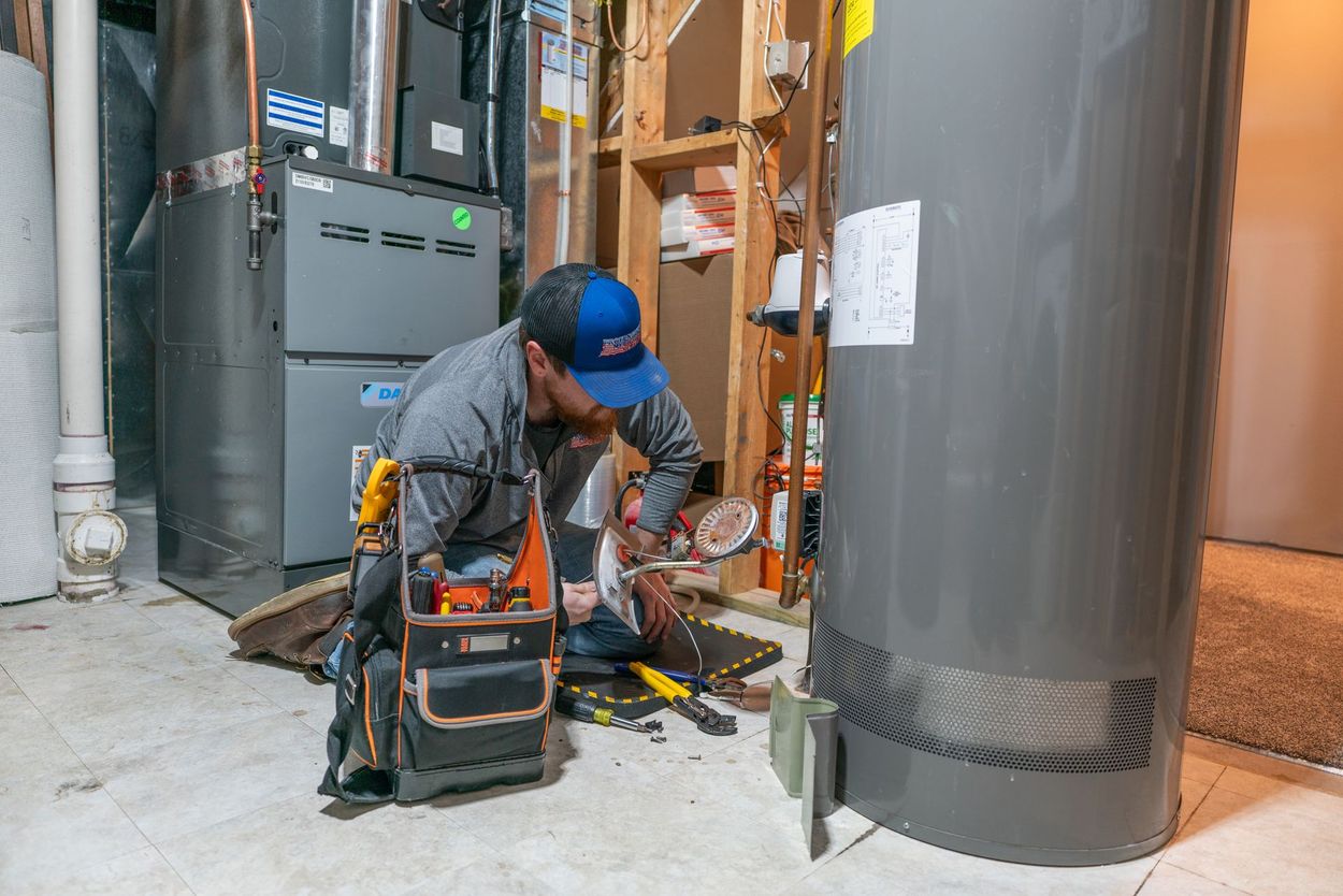 A man is working on a water heater in a basement.