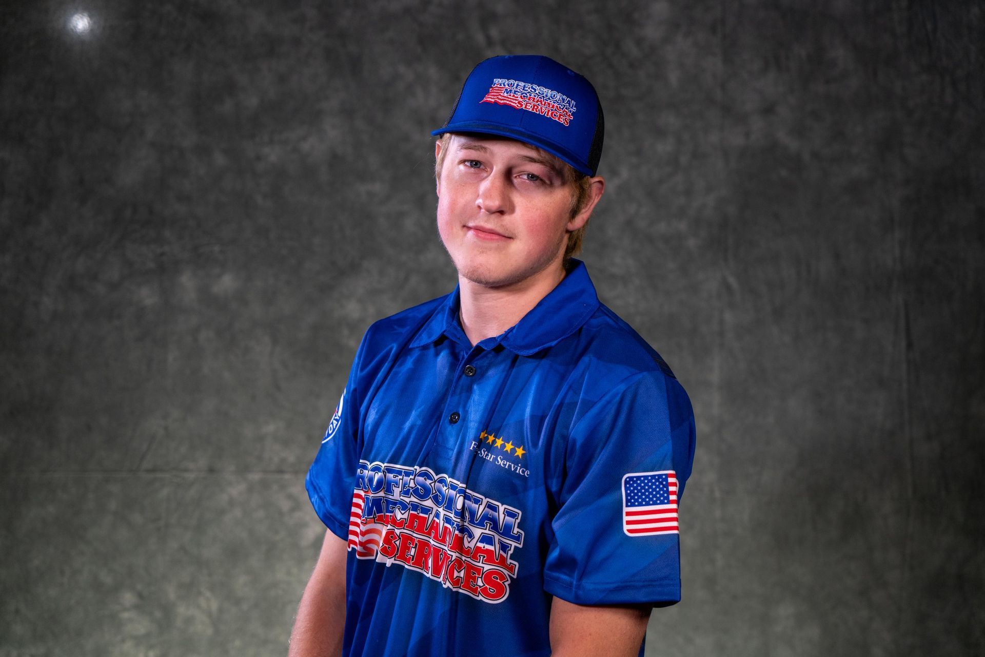 A young man wearing a hat and a black polo shirt
