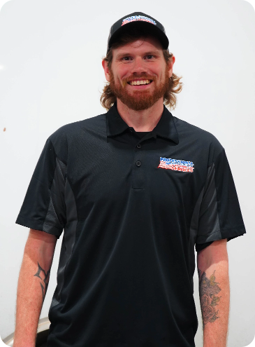 A man with a beard wearing a black polo shirt and a hat