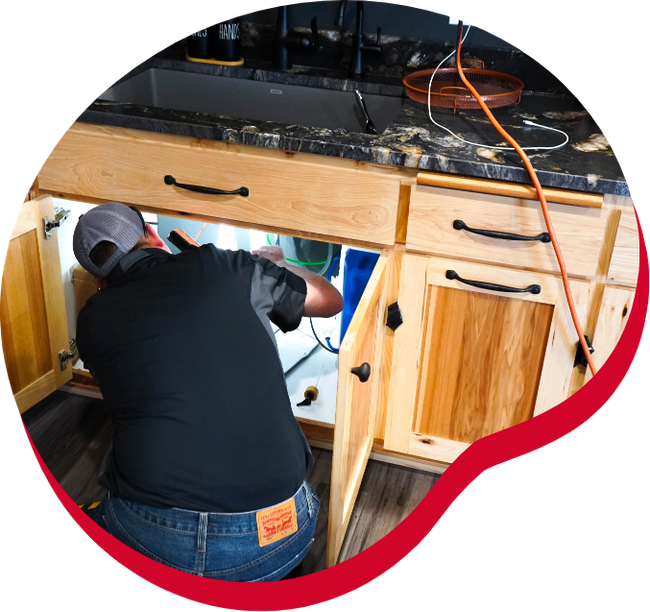 A man is working under a sink in a kitchen