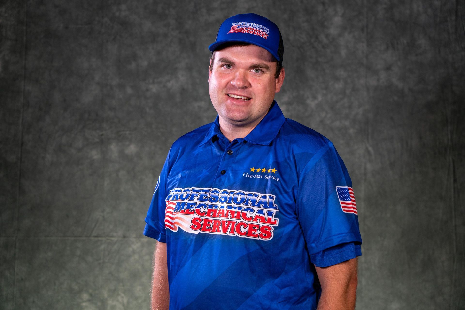 A man wearing a gray shirt and a red hat is smiling