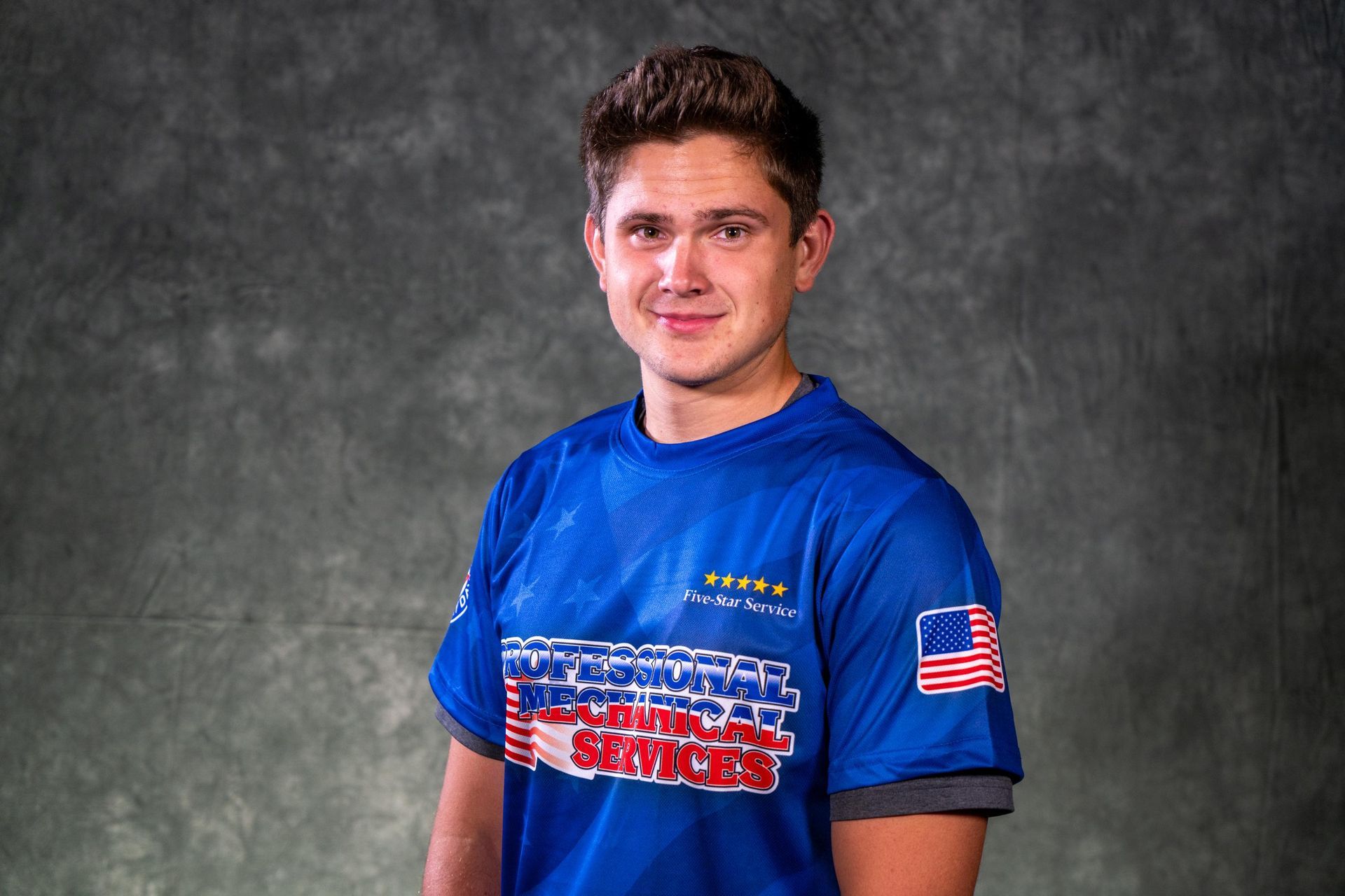 A young man wearing a black polo shirt with a red white and blue logo on the front
