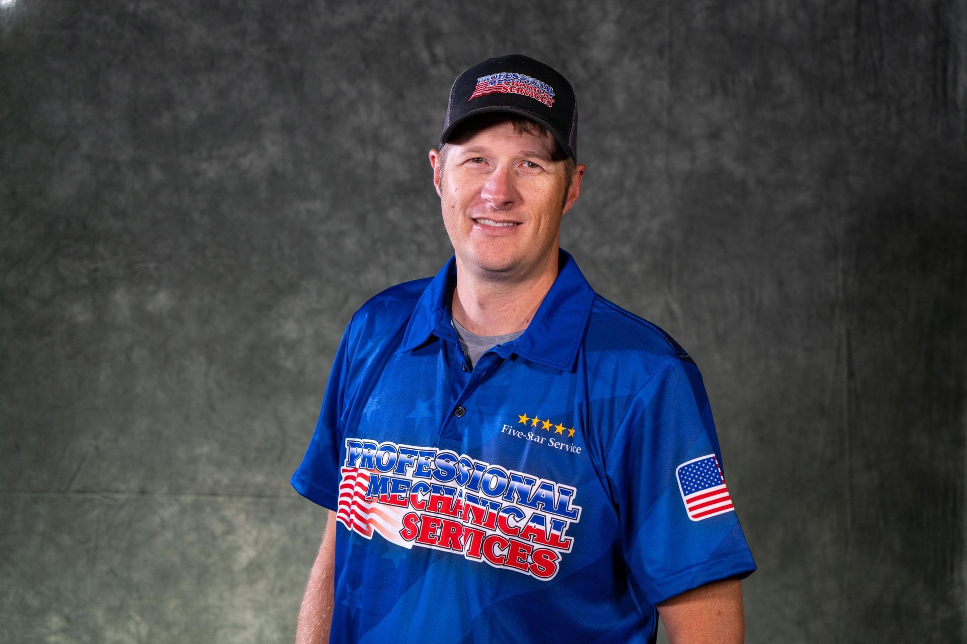 A man wearing a red hat and a black shirt that says jackson motors