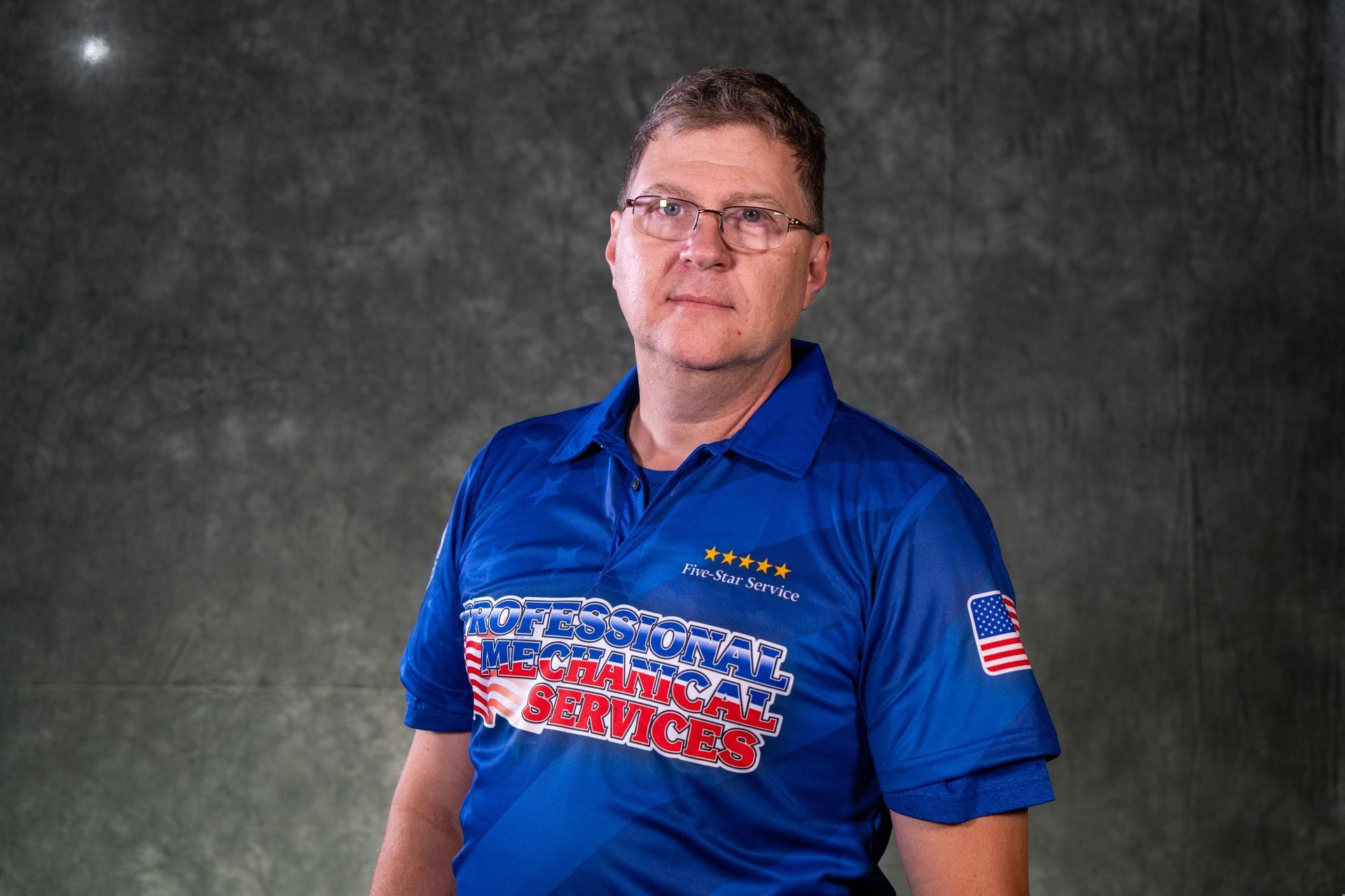 A man wearing glasses and a black shirt with a logo on it
