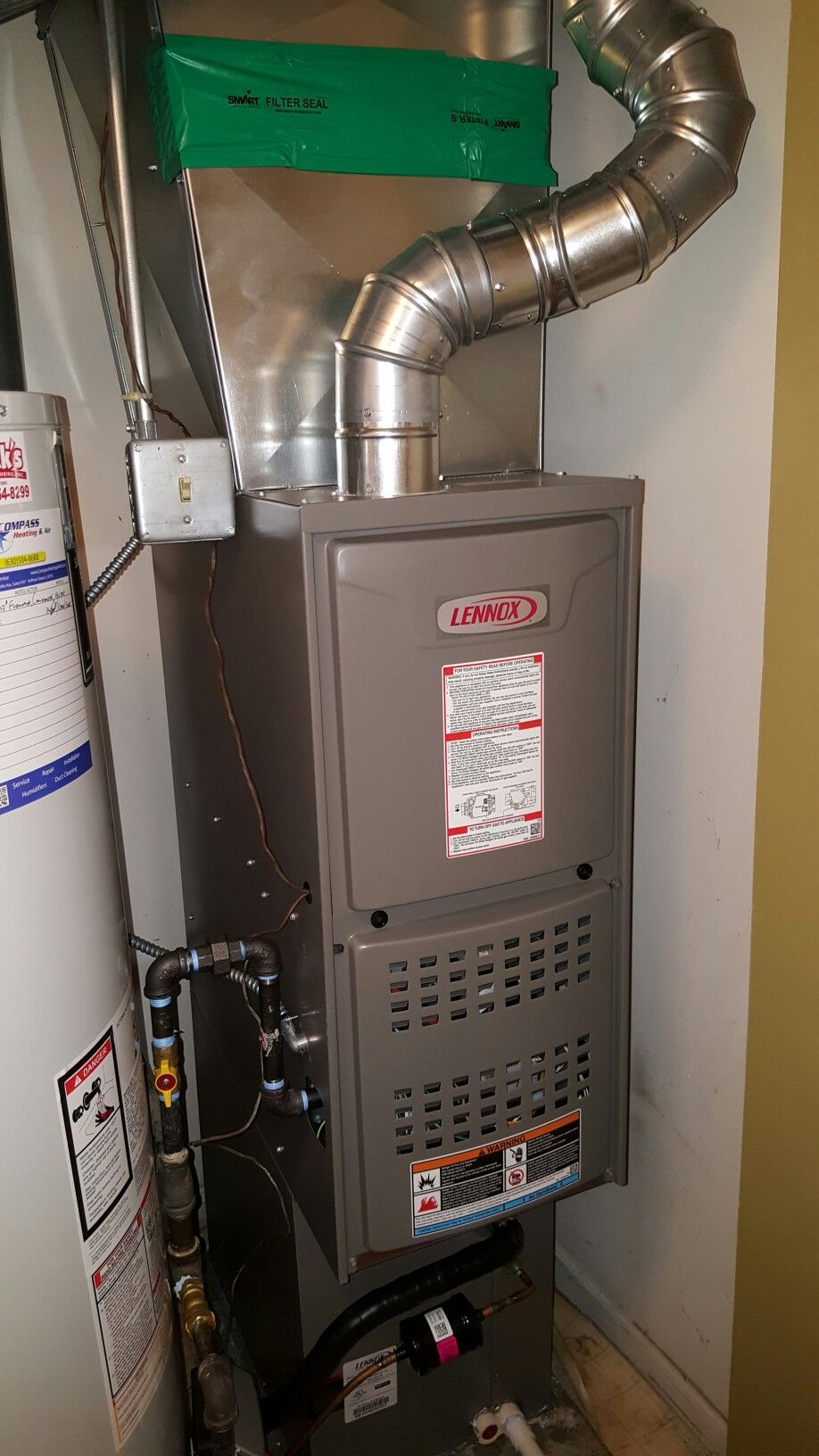 A Lennox furnace and water heater in a utility room. Ductwork and gas lines visible.