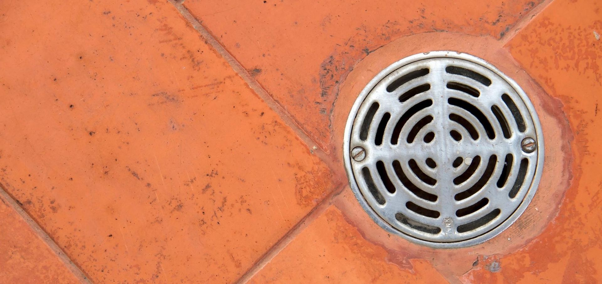 A close up of a drain on a tiled floor.