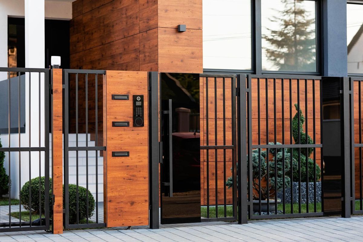 A modern house with a wooden fence and a metal gate.
