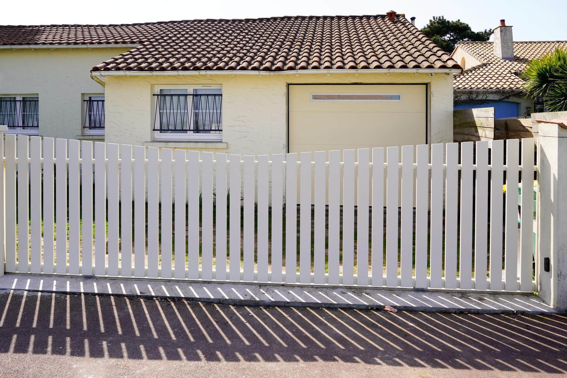 A white picket fence is in front of a house