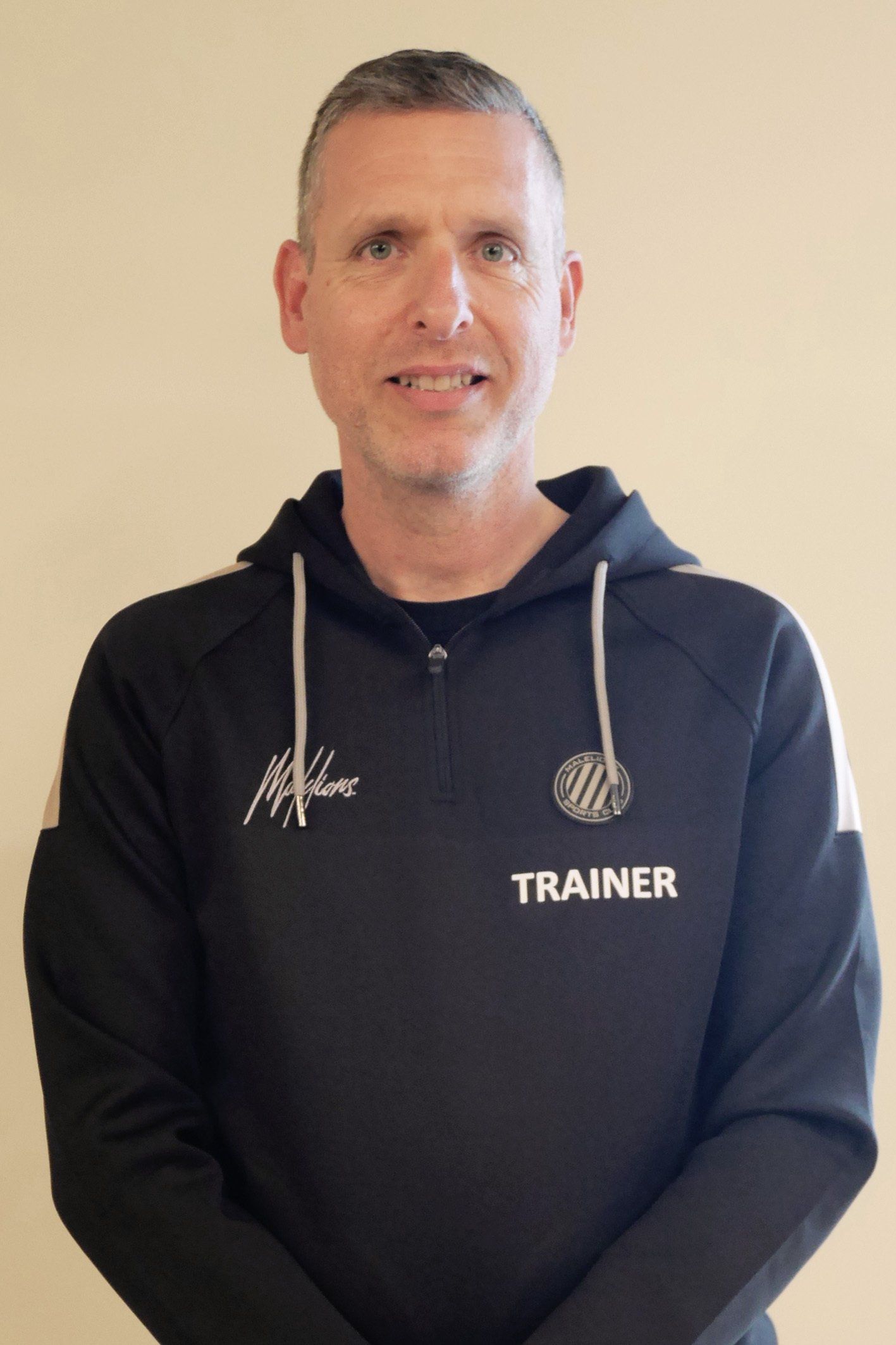 Een man die een hoodie draagt ​​met de tekst 'trainer' erop