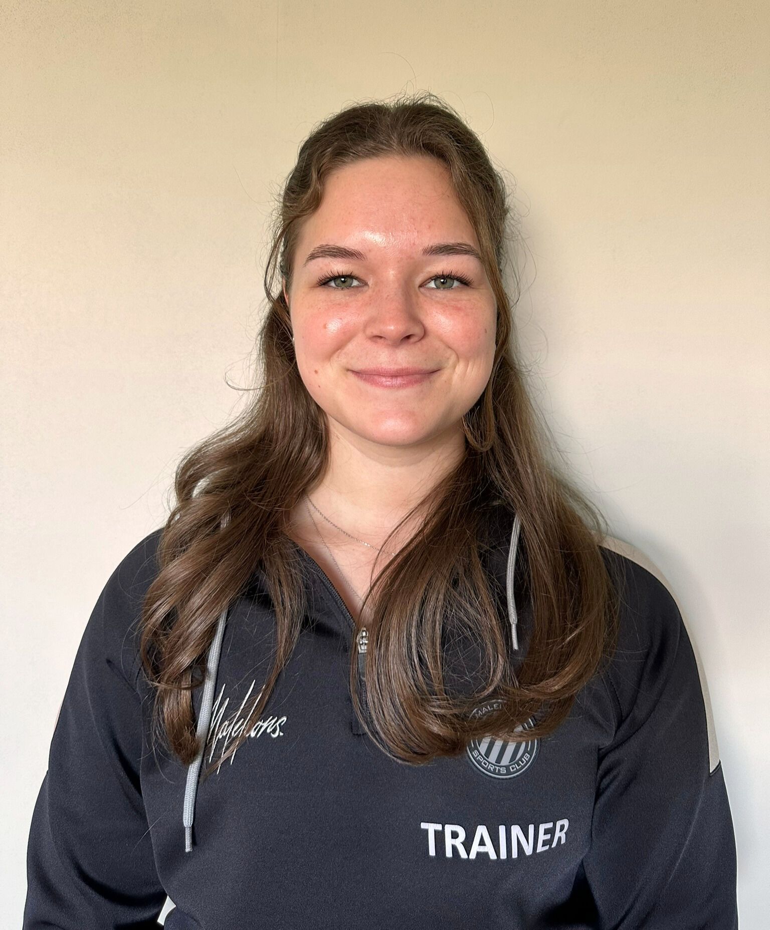 Een vrouw die een zwart shirt draagt ​​met de tekst trainer erop