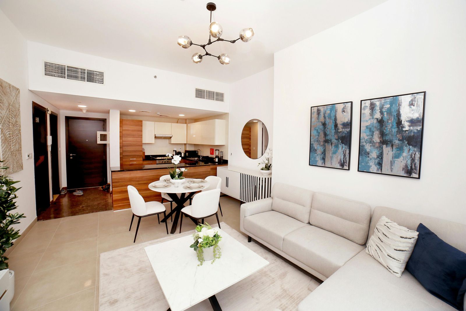 A living room with a couch , table and chairs and a kitchen in the background.