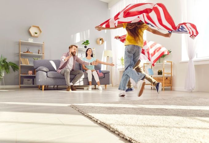 A family is playing with an american flag in a living room.