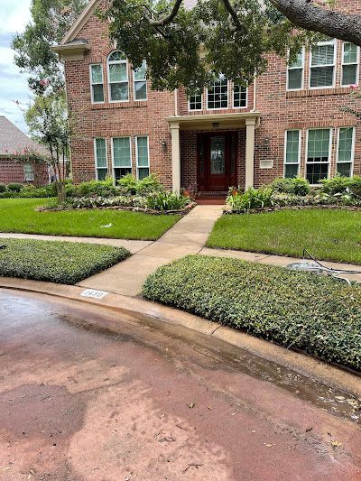 A large brick house with a lush green lawn and a walkway leading to the front door.