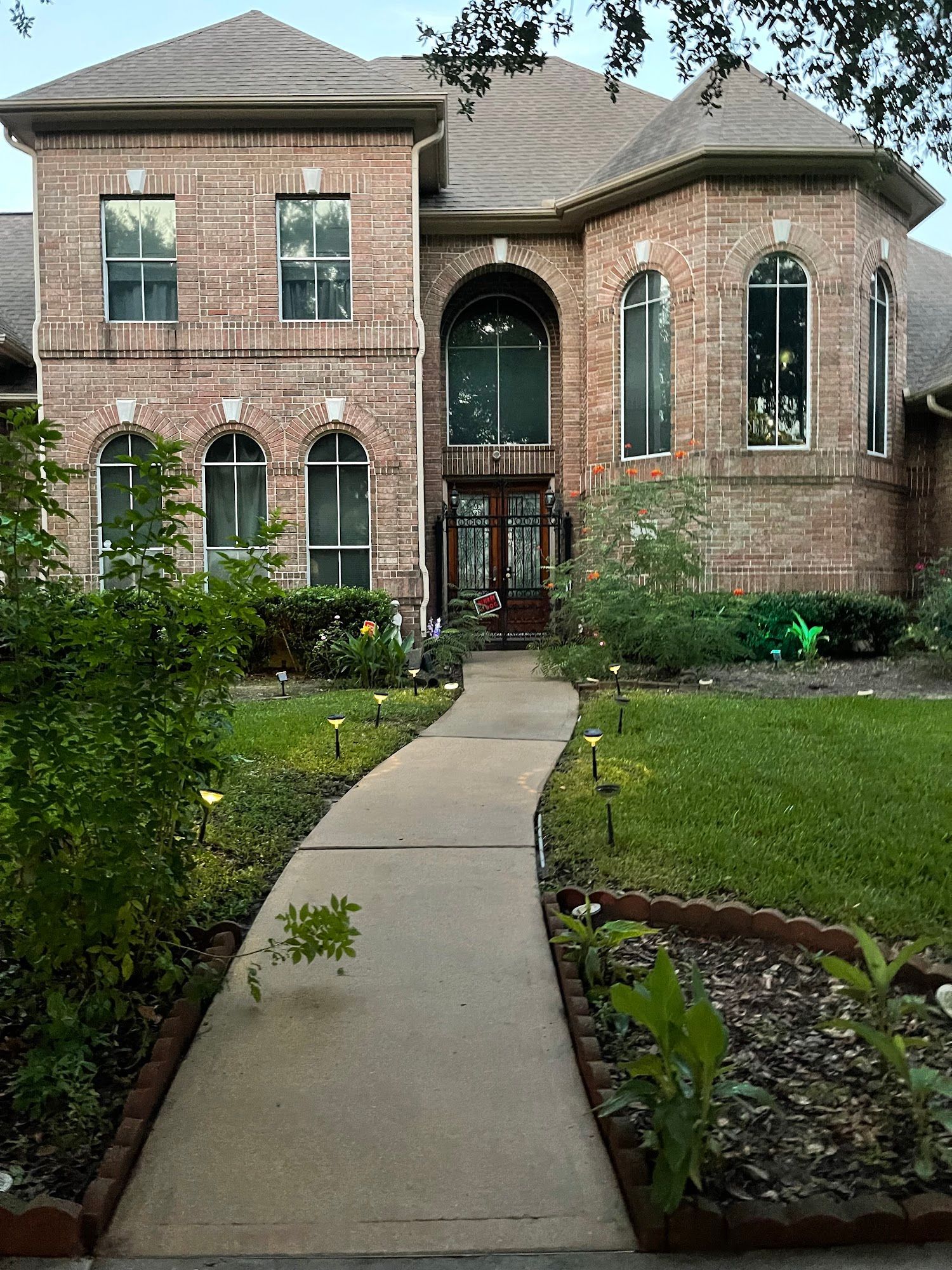A large brick house with a walkway leading to the front door.