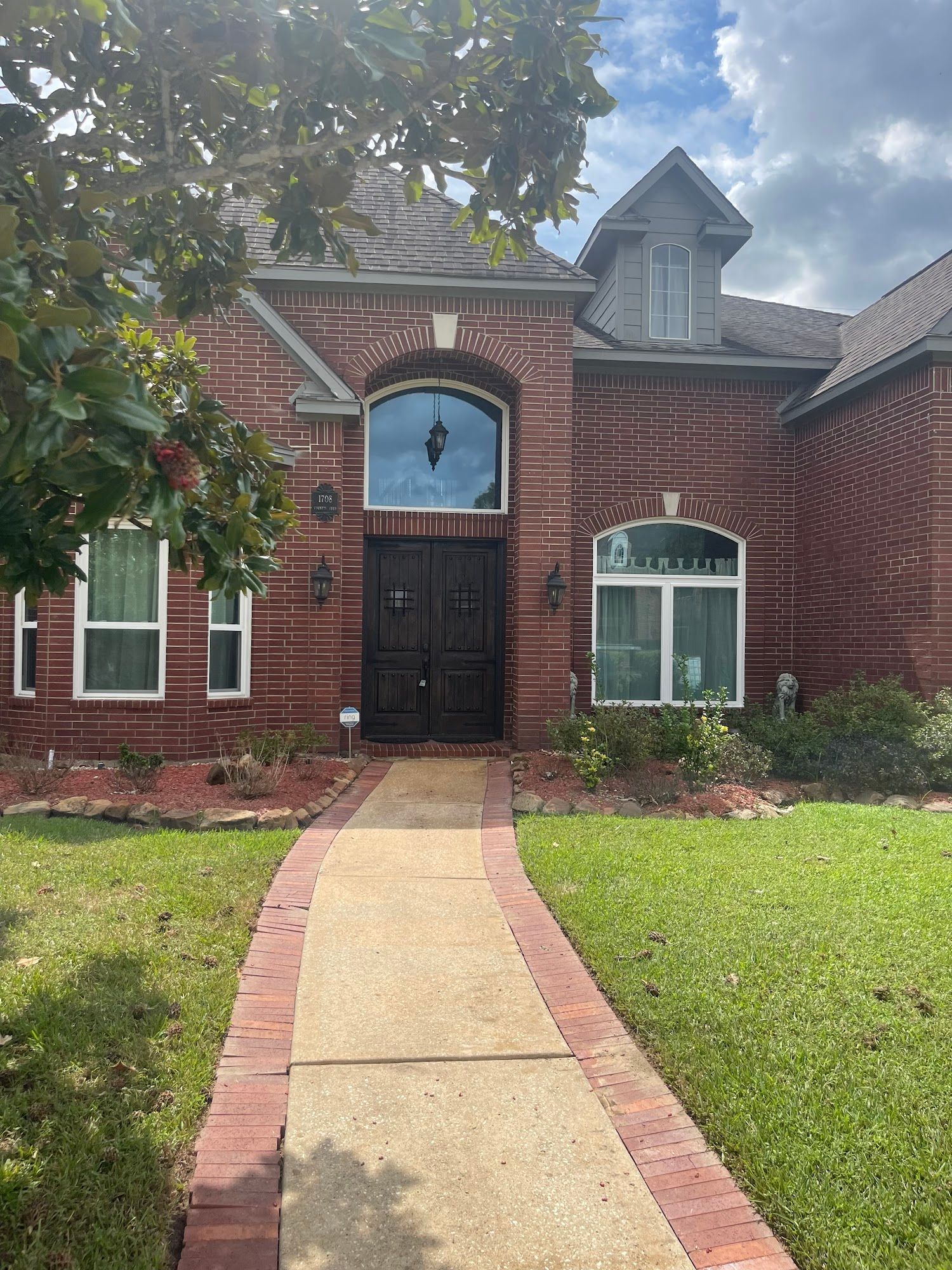 A brick house with a walkway leading to the front door.
