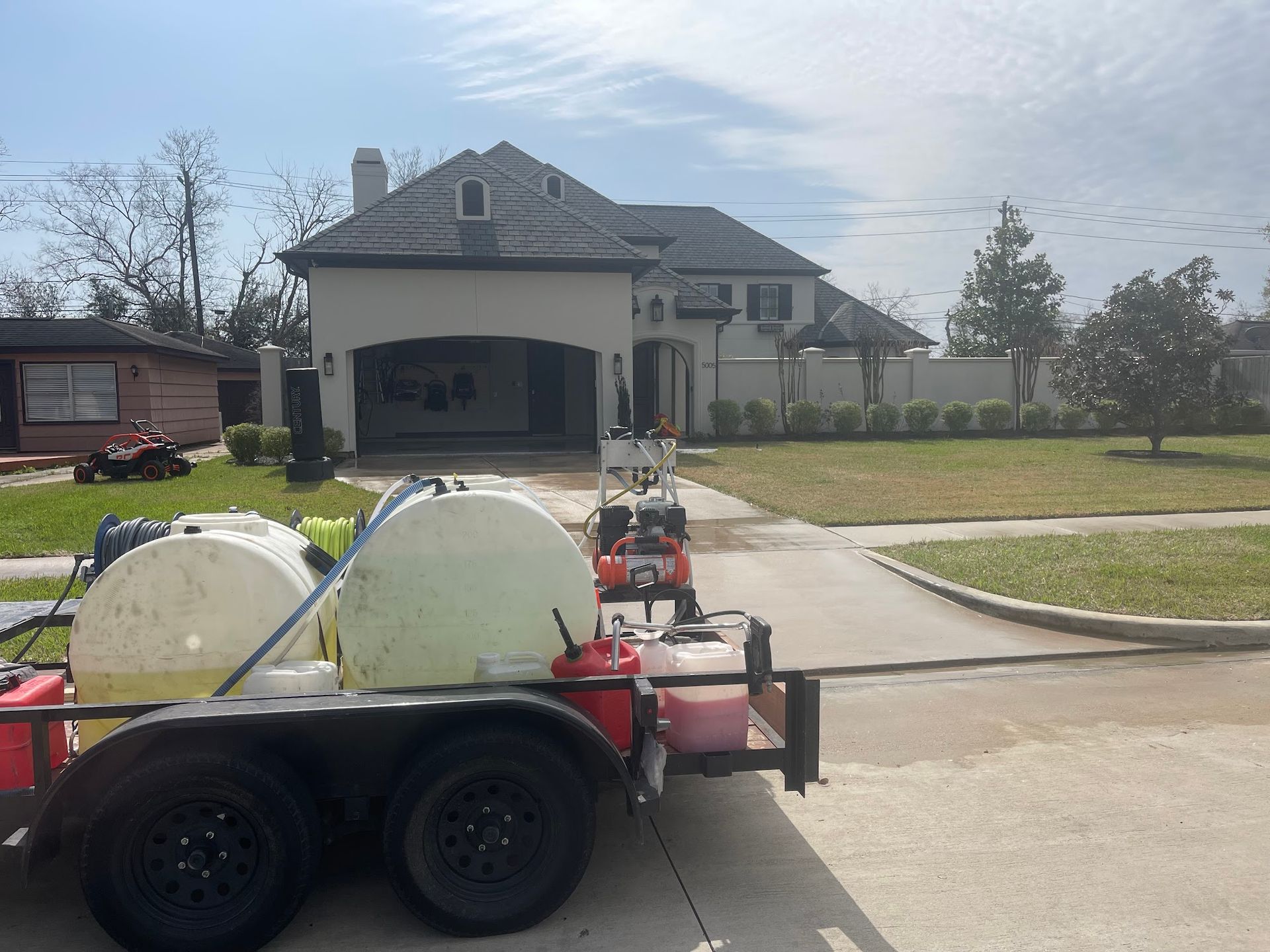 A trailer with a hose attached to it is parked in front of a house.