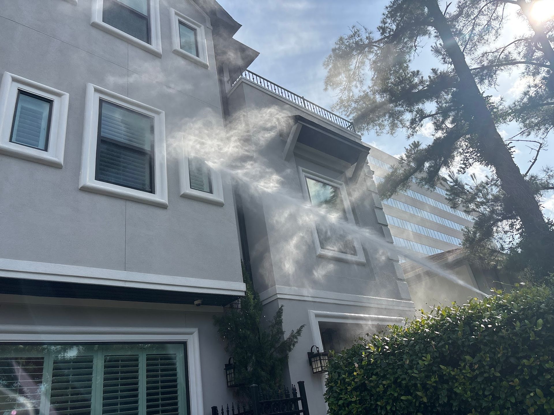 A house with a lot of windows is being sprayed with water.