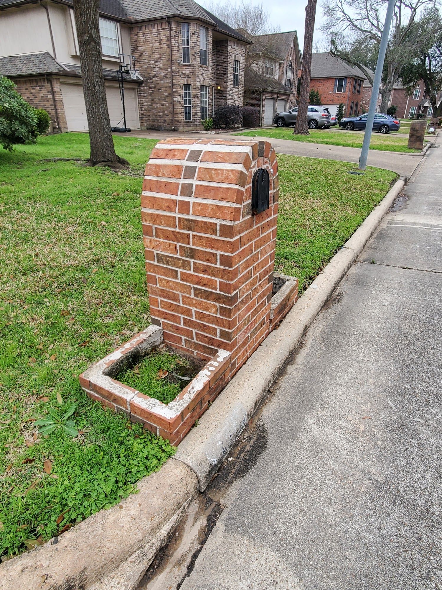 A brick mailbox is sitting on the side of the road.